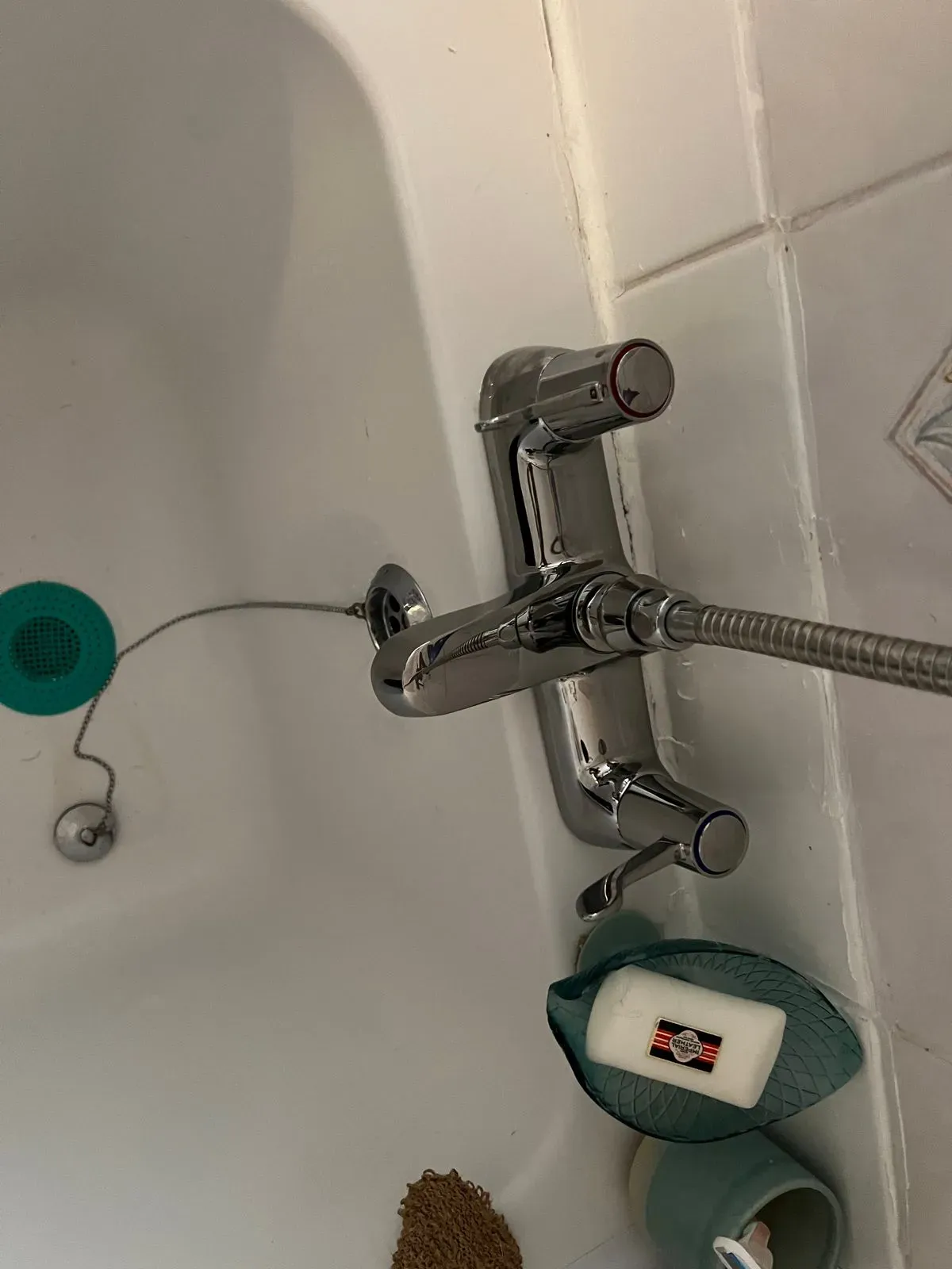 Chrome bath mixer tap with shower handset on a newly fitted bath